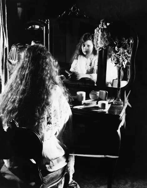 Жінка за столом, дивлячись у дзеркало — стокове фото