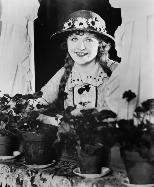 Портрет женщины в окне с цветочными горшками — стоковое фото