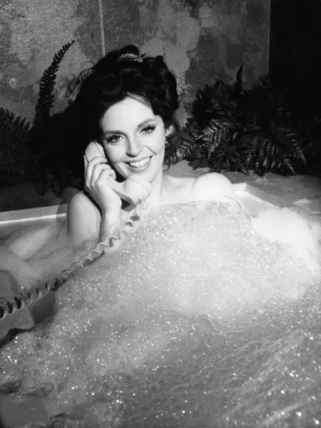 Femme parlant au téléphone dans le bain moussant — Photo