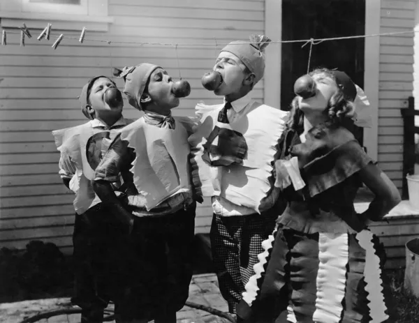 Niños mordiendo manzanas con cuerdas en Halloween —  Fotos de Stock