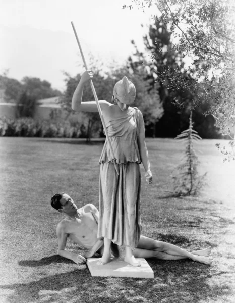 Hombre desnudo afuera con estatua de mujer con lanza —  Fotos de Stock