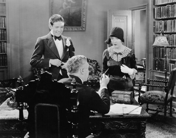 Мужчина за столом разговаривает с женщиной и молодым человеком
