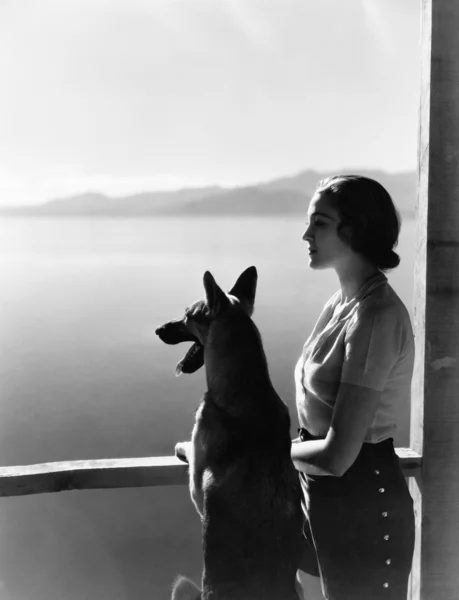 Vrouw en uitkijkend over water hond. — Stockfoto