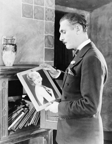 Мужчина смотрит на фотографию женщины
