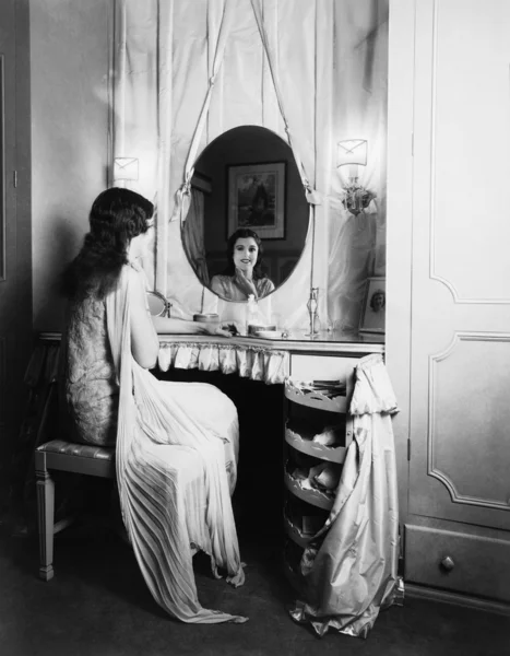 Frau blickt im Spiegel auf Schminktisch — Stockfoto