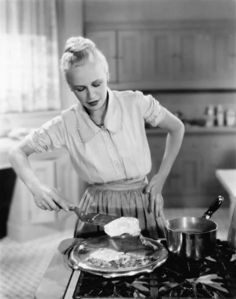 Mujer volteando huevos en la estufa —  Fotos de Stock