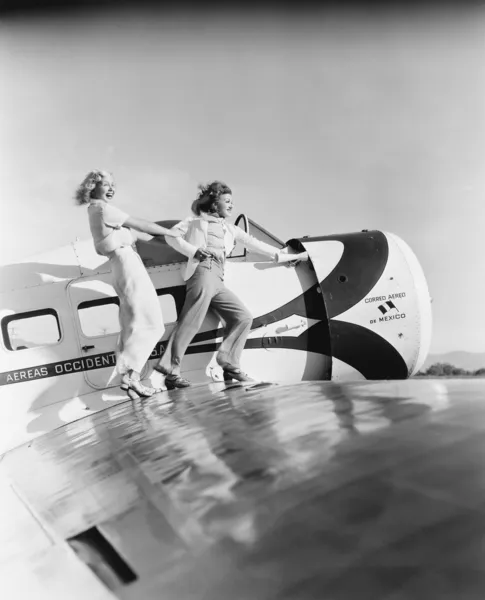 Две женщины, идущие по крылу самолета — стоковое фото
