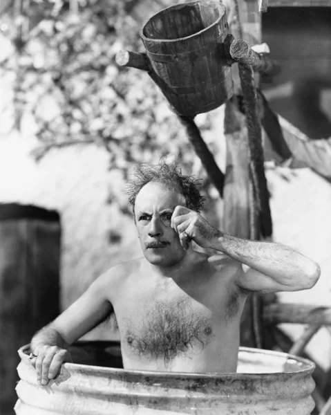 Homem sentado em um barril tomando um banho e olhando através de seu monóculo — Fotografia de Stock