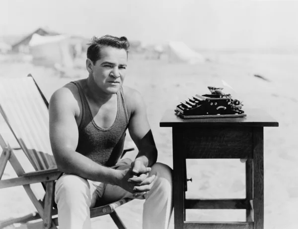 Homem sentado na praia com sua máquina de escrever — Fotografia de Stock
