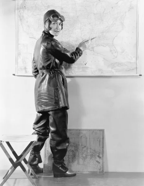 Young woman pointing at a map in a motorcycle outfit — Stock Photo, Image