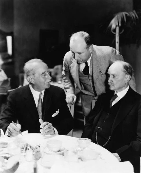 Tři muži seděli spolu u stolu — Stock fotografie