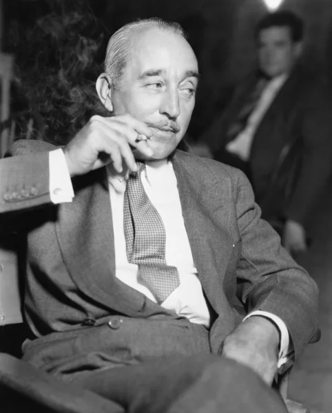 Homem elegante sentado e fumando um cigarro — Fotografia de Stock