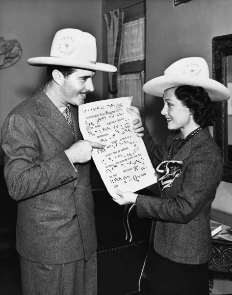 Couple with cowboy hats looking at sheet music — Stock Photo, Image