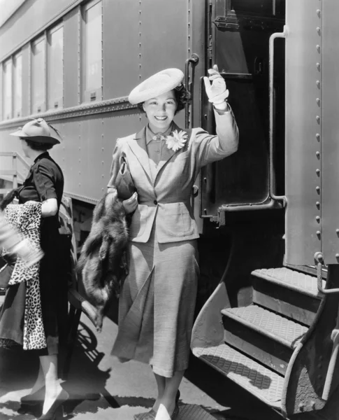 Junge Frau neben Zug winkt — Stockfoto