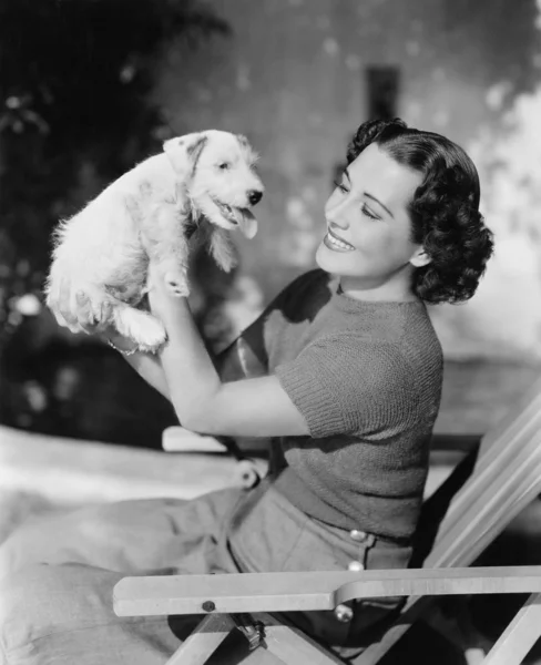 Mujer joven sosteniendo a su cachorro y sonriendo — Foto de Stock