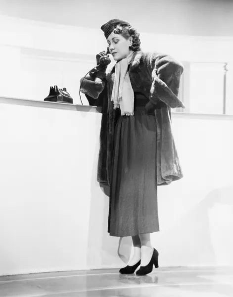 Młoda kobieta, opierając się na licznik i rozmawia przez telefon — Zdjęcie stockowe