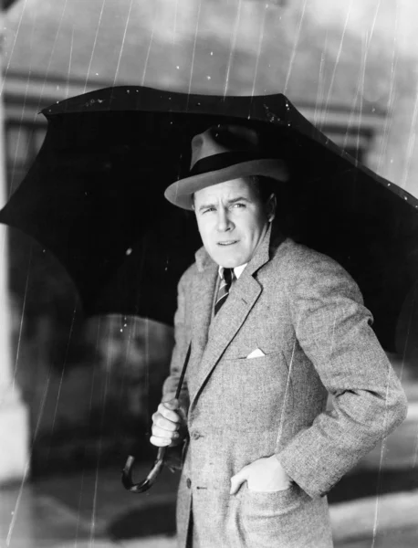 Man med ett paraply som står i regnet — Stockfoto