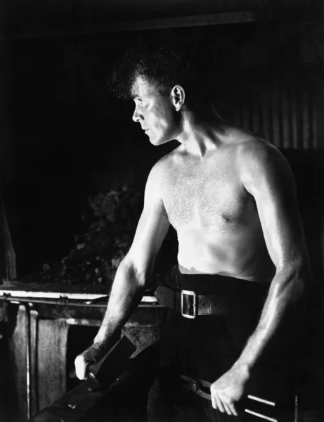 Hombre de pecho desnudo sentado y sosteniendo herramientas en sus manos —  Fotos de Stock
