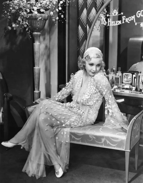 Jeune femme en robe de soirée assise sur un banc rembourré — Photo