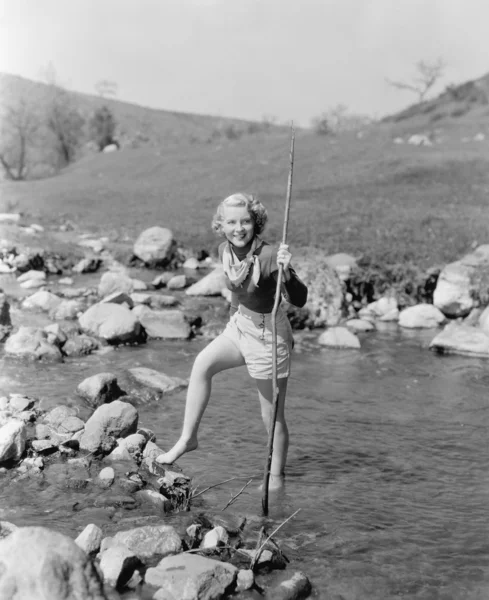 Νεαρή γυναίκα πεζοπορία μέσα από ένα ρεύμα του νερού — Φωτογραφία Αρχείου