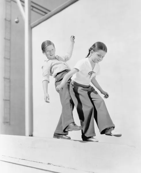 Niño y niña tratando de equilibrar en una cornisa — Foto de Stock