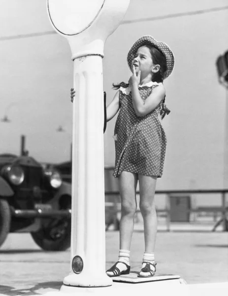 Kleines Mädchen schaut verwirrt auf einer Waage — Stockfoto