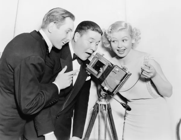 Tre tittar genom en kamera och skrattar — Stockfoto