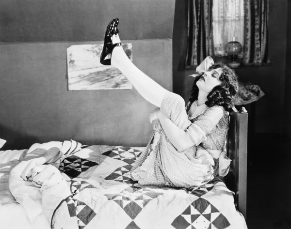 Κορίτσι που κάθεται σε ένα κρεβάτι, τραβώντας τα πόδια της — Φωτογραφία Αρχείου