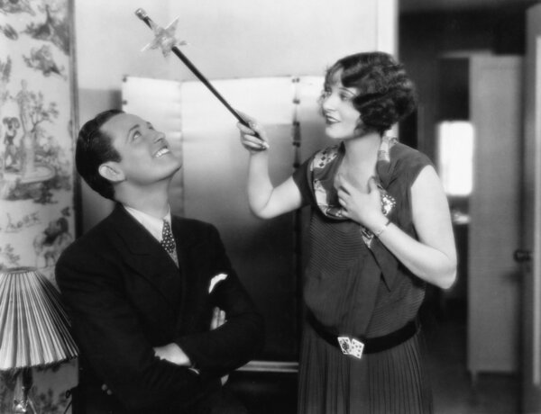 Woman holding a magic wand over her friends head