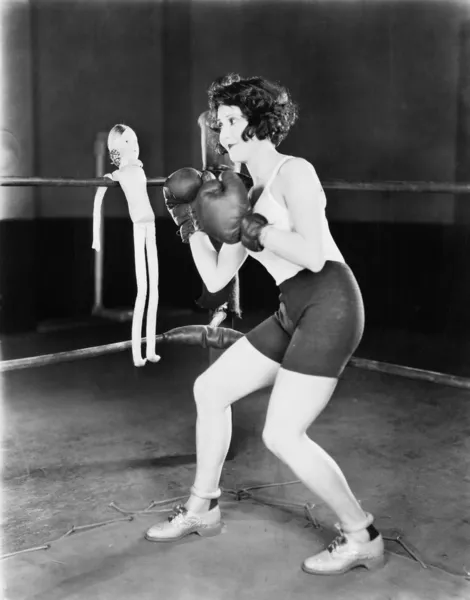 Jonge vrouw met bokshandschoenen met een pop op de touwen — Stockfoto