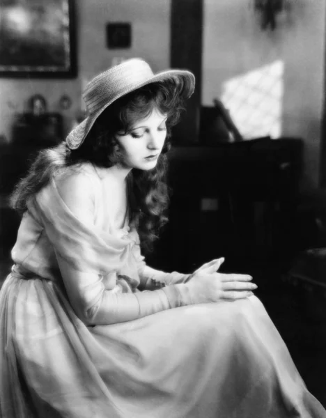 Νεαρή γυναίκα σε ένα καπέλο, καθιστικό και στην εξέταση λυπημένος — Φωτογραφία Αρχείου