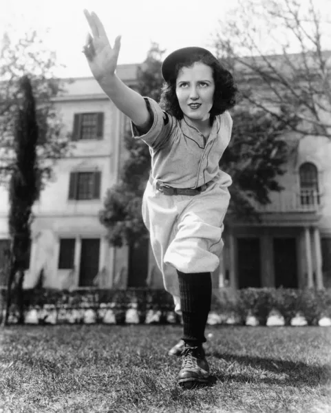 Молода жінка в бейсбольній формі кидає м'яч — стокове фото