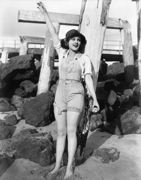 С песком между пальцами ног, молодая женщина машет на пляже — стоковое фото