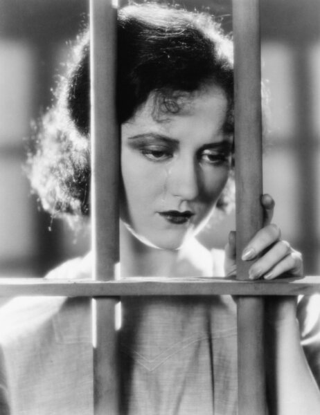 Young woman in a jail, looking sad