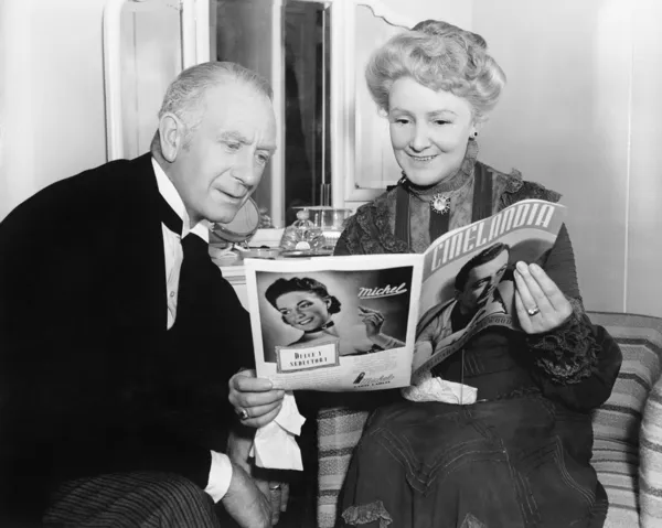 Couple sitting together and looking at a magazine — Stock Photo, Image