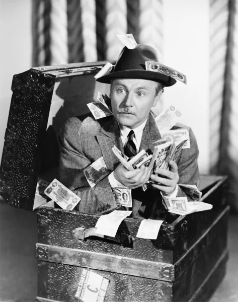 Muž sedící v kufru s penězi v jeho rukou — Stock fotografie