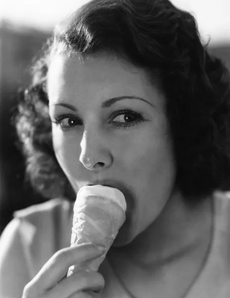Ein kleiner Klecks auf der Nase reicht, wenn eine junge Frau Eis aus einer Tüte isst. — Stockfoto
