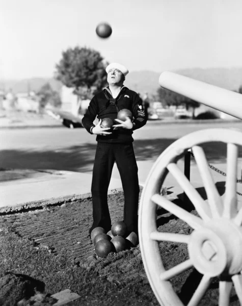 Чоловік у матросах у формі намагається жонглювати гарматні кульки — стокове фото