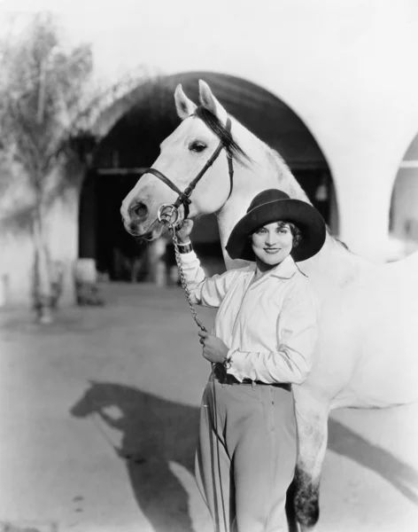 Mujer joven de pie orgullosamente con su caballo — Foto de Stock
