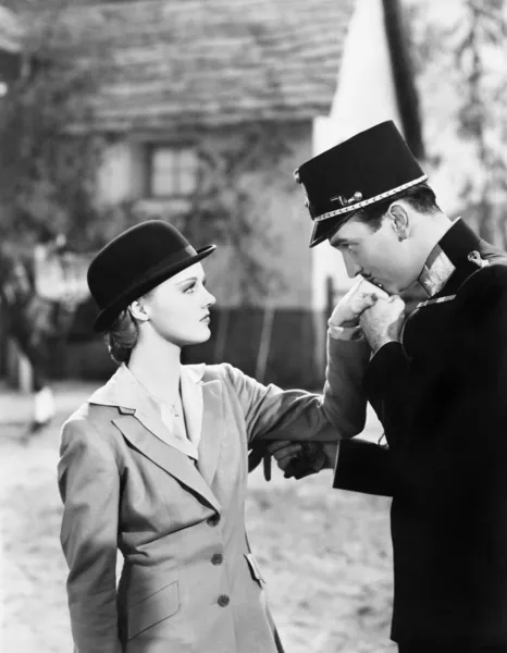 Homem de uniforme beijando a mão de uma jovem mulher — Fotografia de Stock