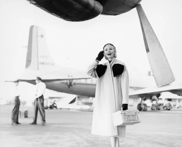 Joven mujer de pie junto a un avión mirando feliz —  Fotos de Stock