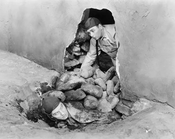 Dois homens a rastejar para fora de um buraco numa parede — Fotografia de Stock