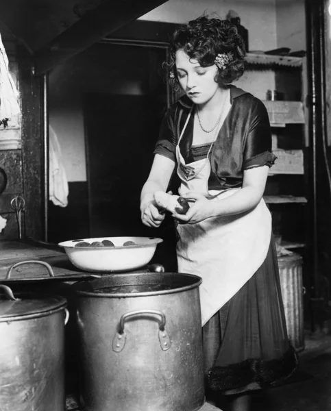 Žena v kuchyni, loupání brambor — Stock fotografie