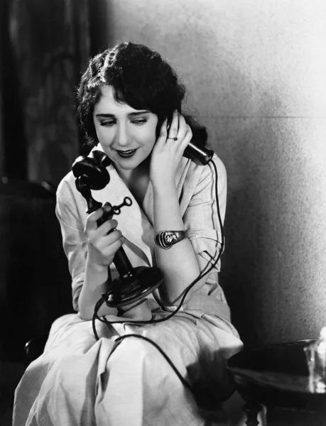 Telefonda konuşurken bir sandalyede oturan genç kadın — Stok fotoğraf