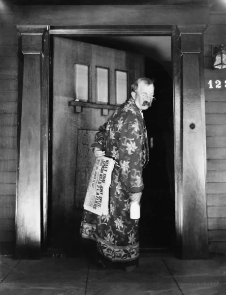 Άντρας με τα πόδια στο σπίτι με την εφημερίδα και το γάλα στο χέρι — Φωτογραφία Αρχείου