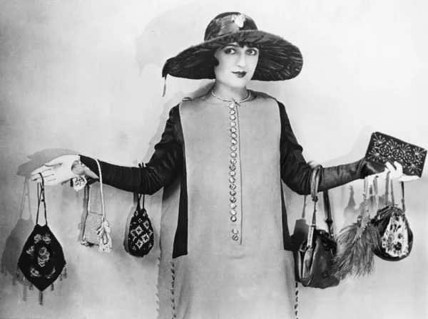Женщина, стоящая с распростертыми руками в сумочках — стоковое фото