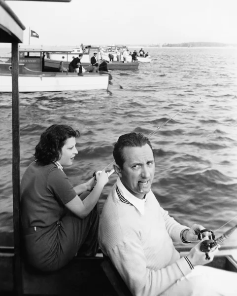 Homme et femme assis sur un bateau sur un lac avec leur canne à pêche — Photo
