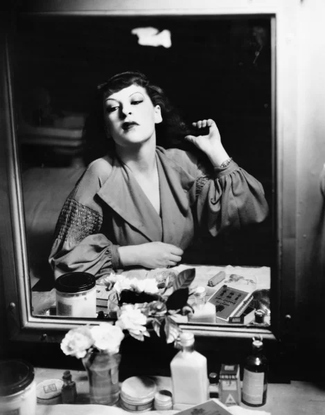 Mujer sentada frente a su vanidad mirando al espejo — Foto de Stock