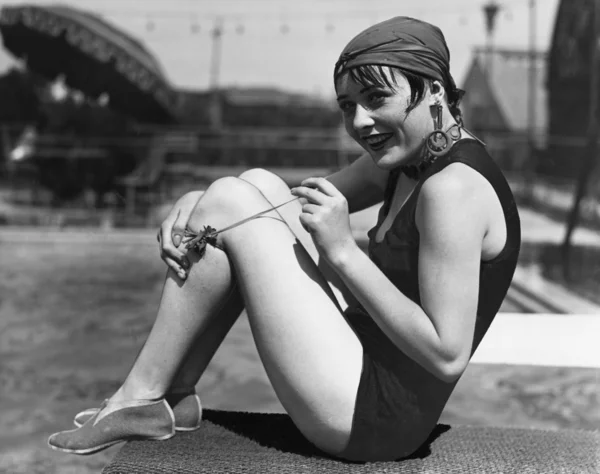 Retrato de uma mulher com um cachecol ao redor da cabeça sentada ao lado da piscina — Fotografia de Stock