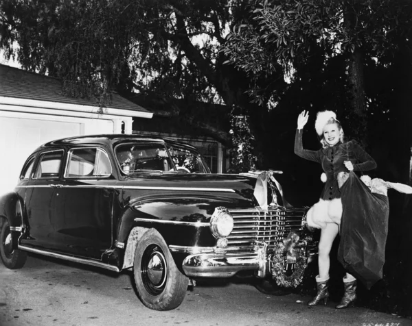 Donna in piedi davanti a una macchina che tiene una borsa di regali di Natale — Foto Stock